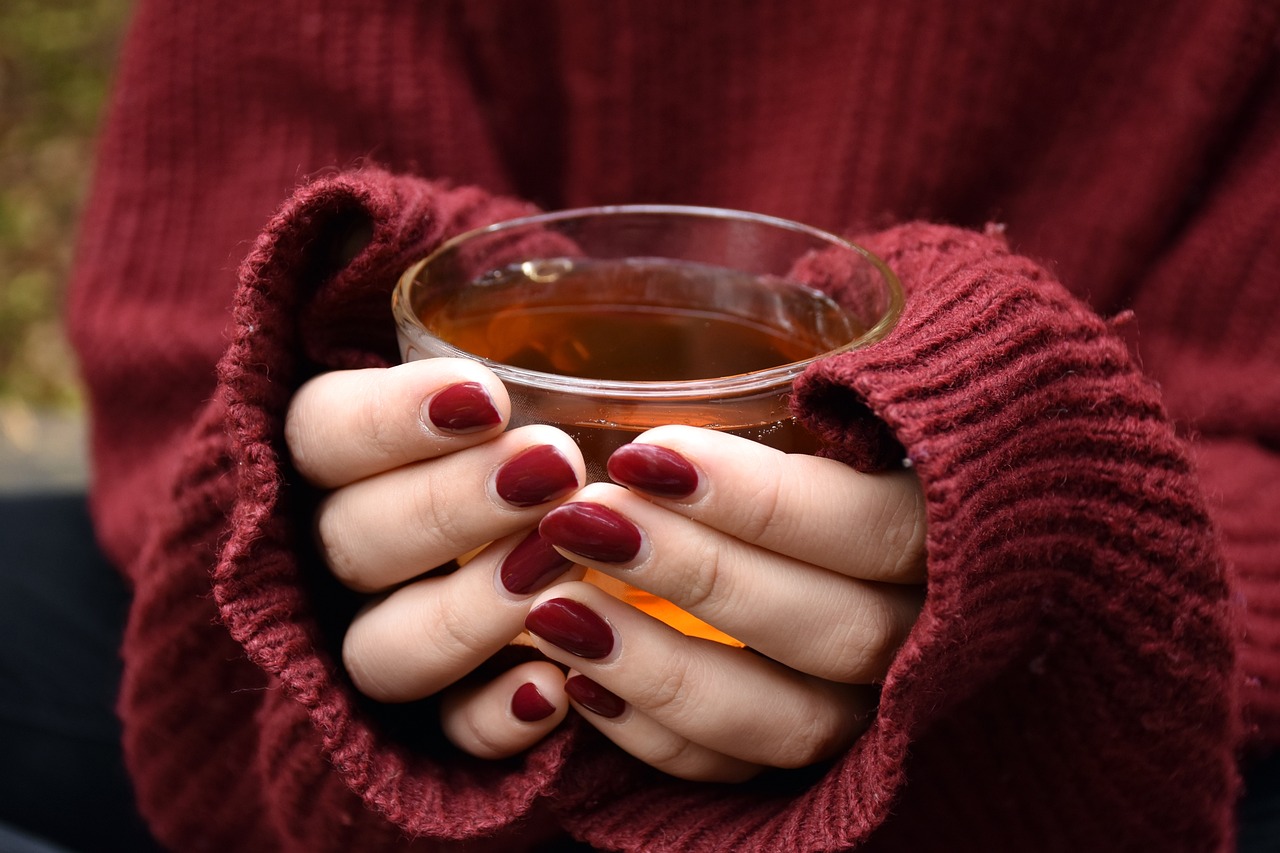 Femme détendue tenant une tasse de thé chaud, profitant d’un moment de bien-être hivernal. L'image illustre l'importance des boissons chaudes et des remèdes naturels, comme les infusions, pour se réchauffer et renforcer le système immunitaire pendant la saison froide. Ce moment de détente favorise également la relaxation et la lutte contre la fatigue hivernale